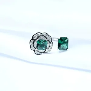 floral adjustable silver ring with green accents displayed on white fabric